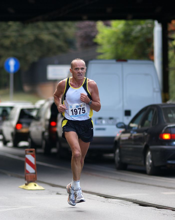 Focused runner participating in a city marathon amidst traffic, showcasing endurance and fitness.